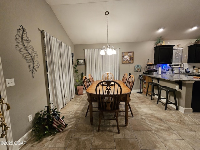 dining space featuring sink, light tile patterned floors, a chandelier, and vaulted ceiling