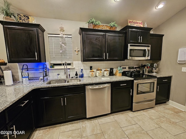 kitchen with lofted ceiling, sink, light stone countertops, light tile patterned floors, and stainless steel appliances