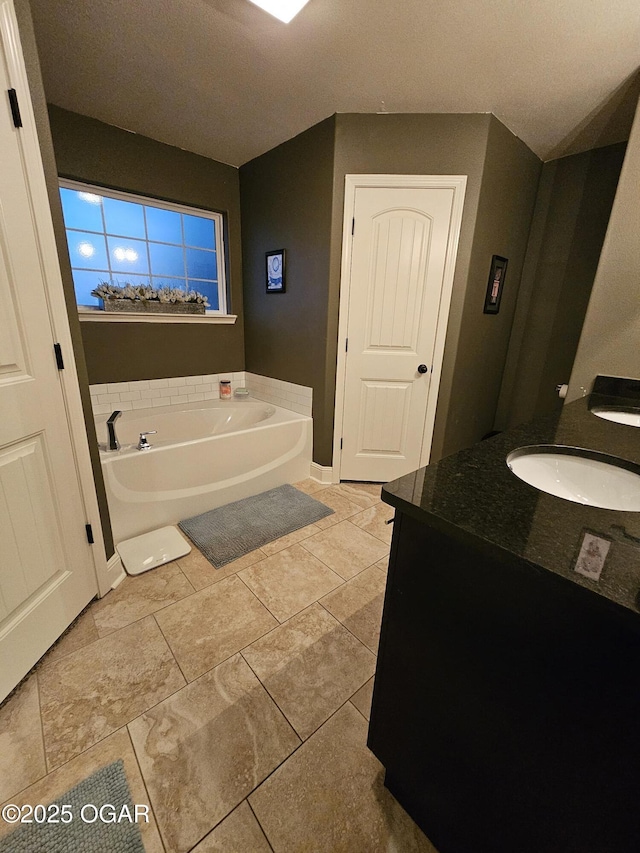 bathroom with a washtub, vanity, and tile patterned flooring