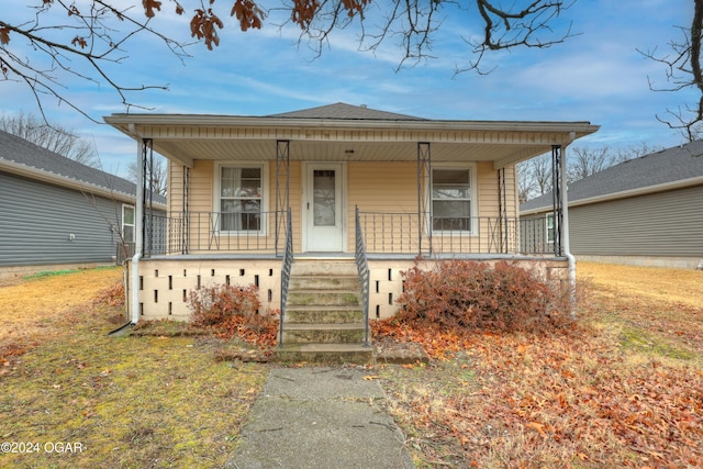 bungalow-style house featuring covered porch and a front yard