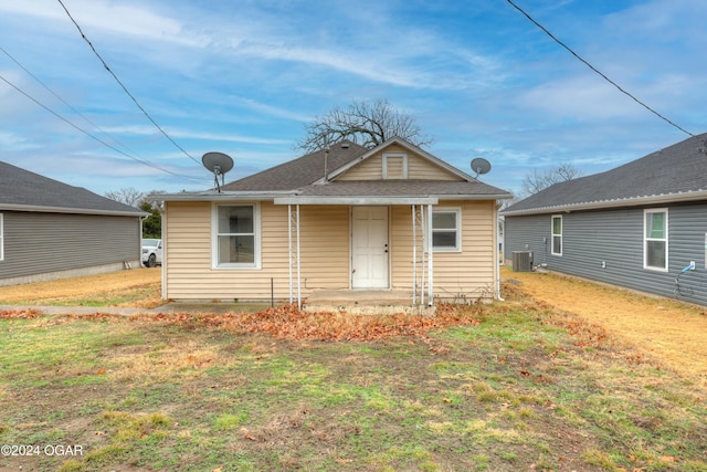 bungalow-style home featuring a front lawn and central AC unit