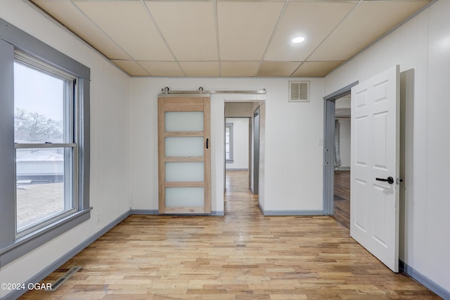 spare room with a paneled ceiling and light hardwood / wood-style flooring