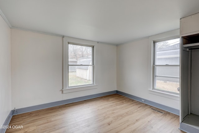 empty room with light hardwood / wood-style floors and ornamental molding