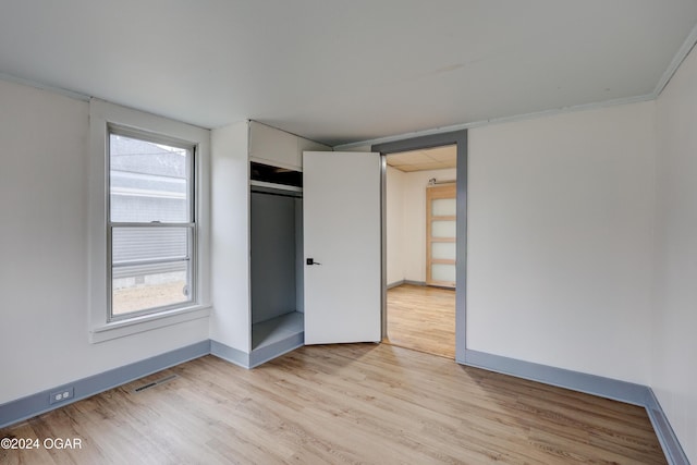 unfurnished bedroom with multiple windows, a closet, and light wood-type flooring