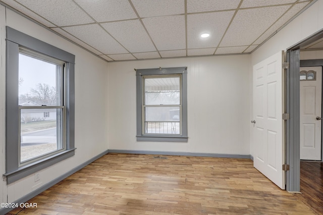 unfurnished room featuring light hardwood / wood-style flooring and a drop ceiling