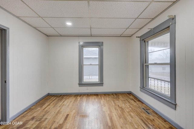 unfurnished room with light hardwood / wood-style floors and a drop ceiling