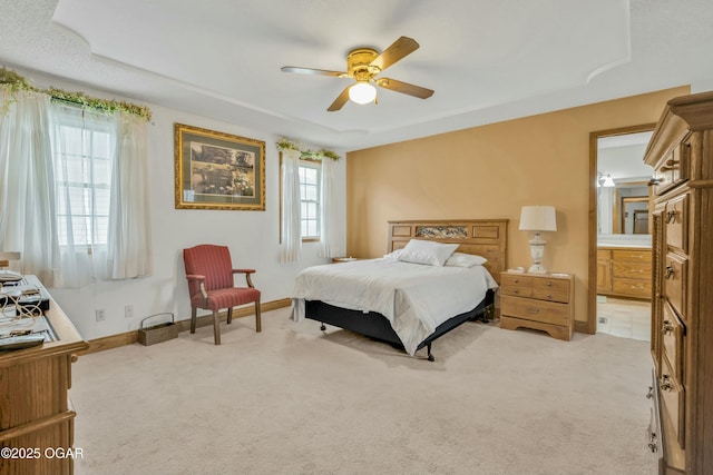 carpeted bedroom featuring ceiling fan, multiple windows, and ensuite bath