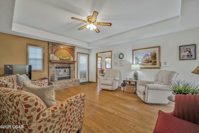 living room featuring a tray ceiling, light hardwood / wood-style flooring, and ceiling fan