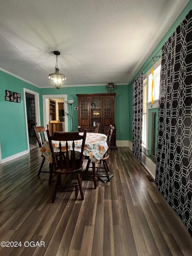 dining room featuring dark wood-type flooring, ornamental molding, a textured ceiling, and a notable chandelier