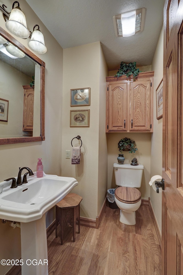 bathroom featuring hardwood / wood-style floors, toilet, and a textured ceiling