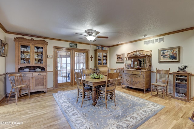 dining area with light hardwood / wood-style flooring, a textured ceiling, and ornamental molding