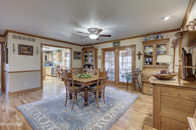 dining space with a textured ceiling, ceiling fan, light wood-type flooring, and ornamental molding