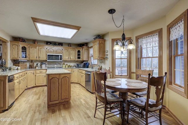 kitchen featuring tasteful backsplash, a kitchen island, light hardwood / wood-style floors, and an inviting chandelier