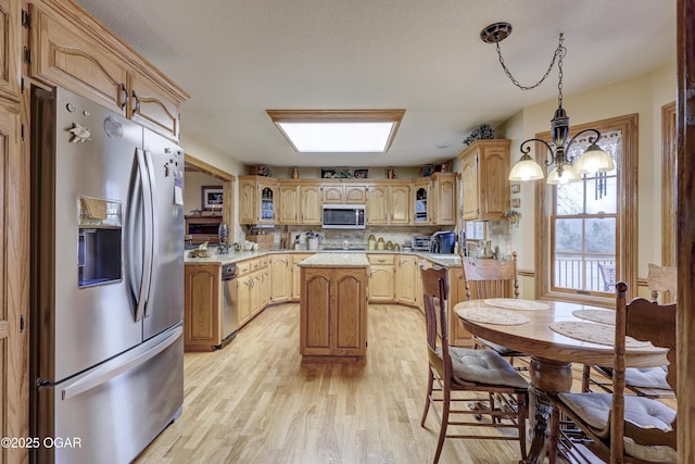 kitchen with hanging light fixtures, appliances with stainless steel finishes, tasteful backsplash, a notable chandelier, and a kitchen island