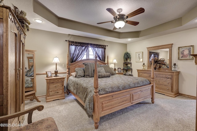 carpeted bedroom featuring ceiling fan, a raised ceiling, and a textured ceiling