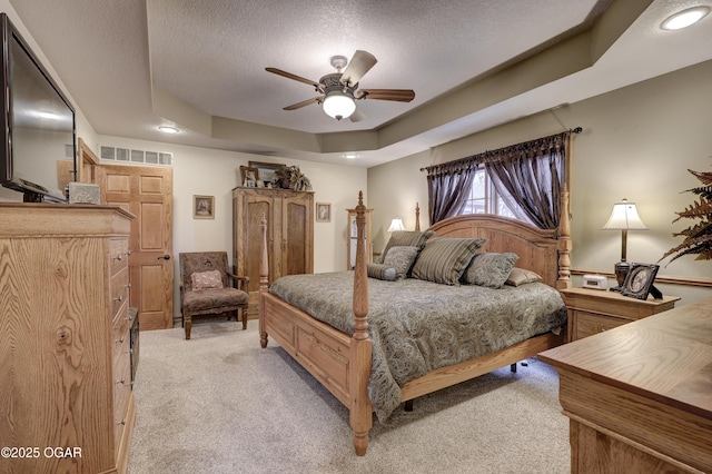 carpeted bedroom with a textured ceiling, a raised ceiling, and ceiling fan