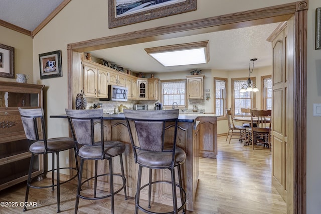 kitchen with hanging light fixtures, a kitchen breakfast bar, a chandelier, lofted ceiling, and decorative backsplash