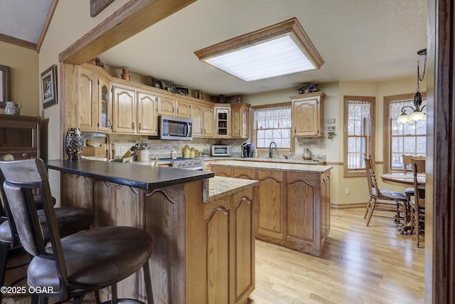 kitchen featuring backsplash, an inviting chandelier, a kitchen breakfast bar, light hardwood / wood-style floors, and kitchen peninsula