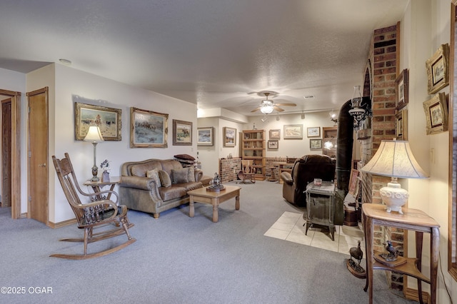 living room featuring a textured ceiling, light colored carpet, a wood stove, and ceiling fan