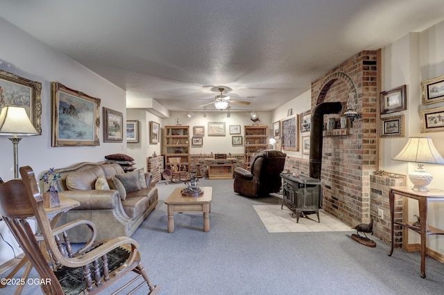 carpeted living room featuring ceiling fan, a wood stove, a textured ceiling, and brick wall