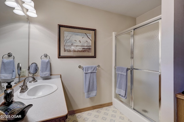 bathroom featuring a shower with shower door and sink