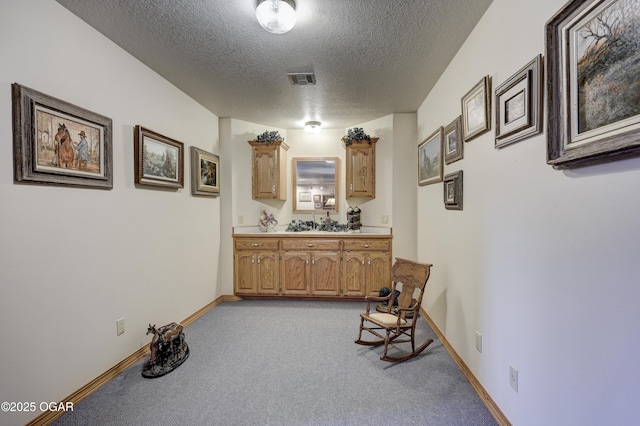 corridor featuring light colored carpet and a textured ceiling