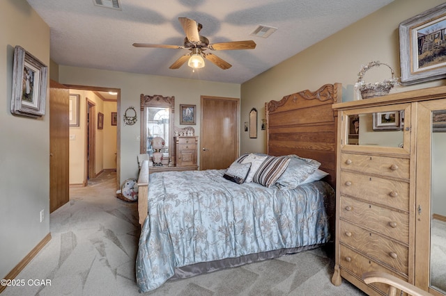 carpeted bedroom featuring ceiling fan and a textured ceiling