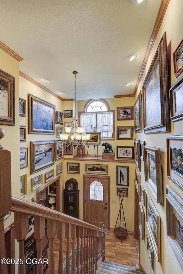 interior space with crown molding, wood-type flooring, a textured ceiling, and an inviting chandelier