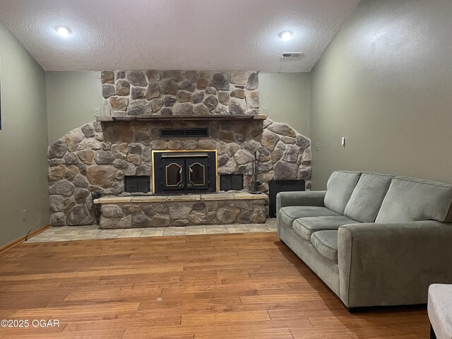 living room with a fireplace, wood-type flooring, and a textured ceiling