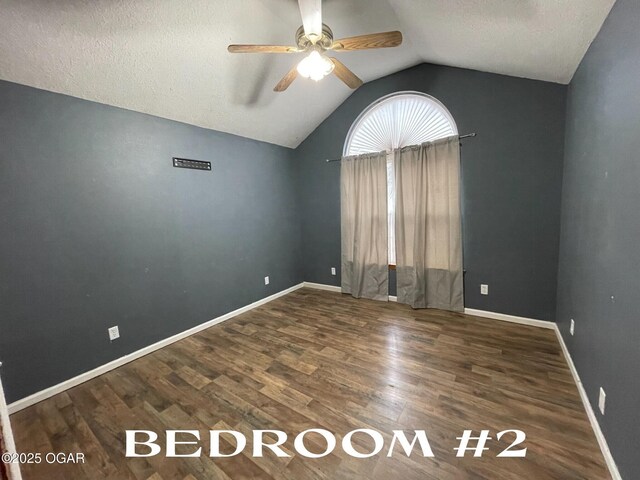 spare room featuring a textured ceiling, ceiling fan, lofted ceiling, and dark wood-type flooring