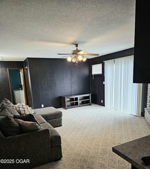 carpeted living room with wood walls, ceiling fan, and a textured ceiling