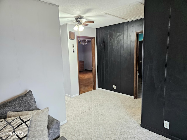 hall featuring a textured ceiling, wood walls, and light carpet