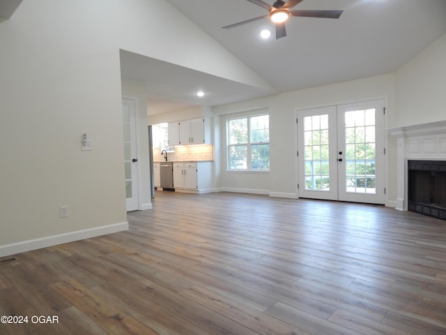 unfurnished living room featuring french doors, light hardwood / wood-style floors, high vaulted ceiling, and ceiling fan