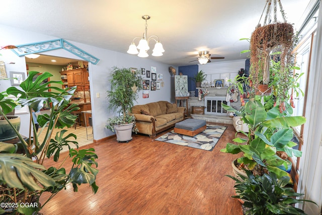 202 Arbor Dr, Lamar, MO 64759 - living room featuring a large fireplace, ceiling fan with notable chandelier, and light wood-type flooring
