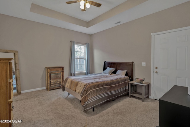 carpeted bedroom featuring a raised ceiling and ceiling fan