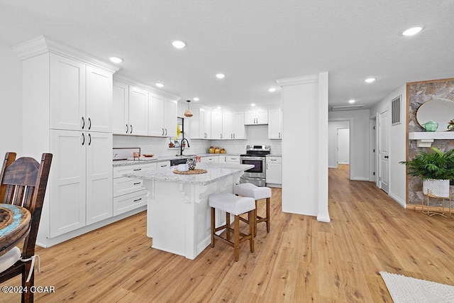 kitchen featuring white cabinets, light hardwood / wood-style floors, and stainless steel range with electric stovetop