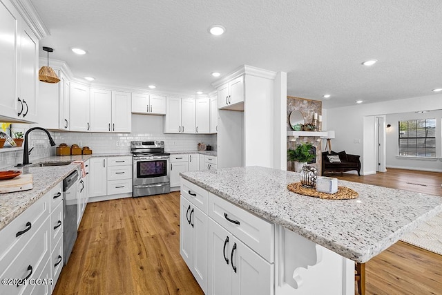 kitchen featuring light hardwood / wood-style flooring, decorative light fixtures, a breakfast bar, white cabinets, and appliances with stainless steel finishes