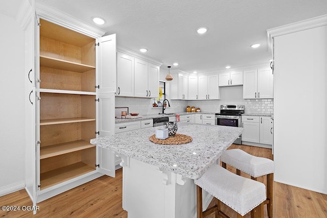 kitchen with a breakfast bar area, light wood-type flooring, light stone countertops, white cabinetry, and stainless steel appliances