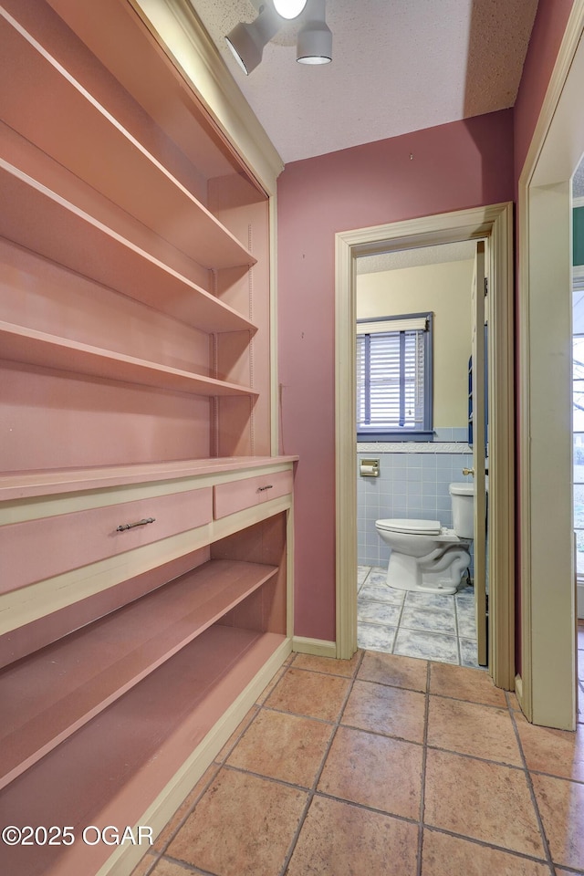 bathroom with toilet and tile walls