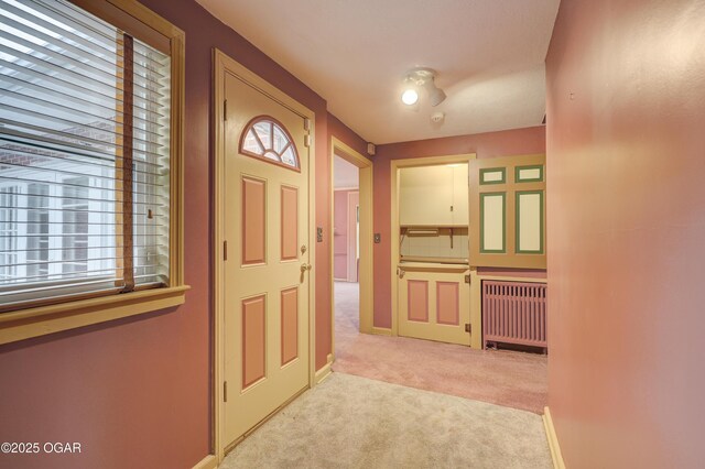 hallway with radiator heating unit and light carpet