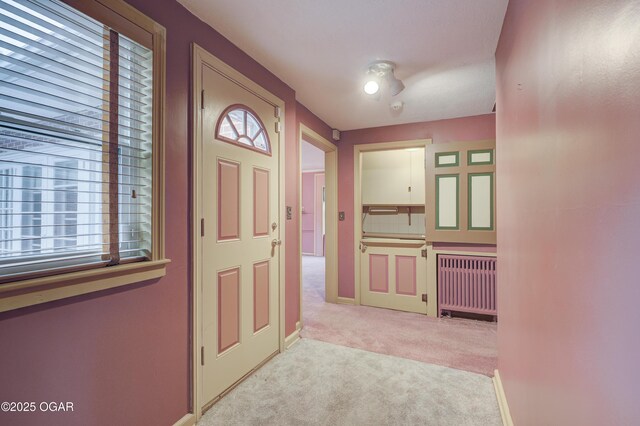 hall featuring light colored carpet and radiator