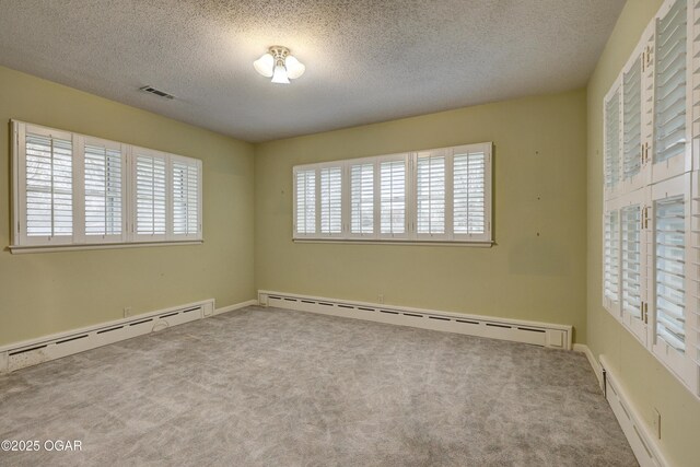 spare room featuring carpet flooring, a textured ceiling, and a baseboard heating unit