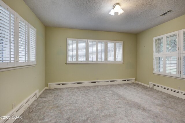 spare room featuring baseboard heating, a wealth of natural light, and a textured ceiling