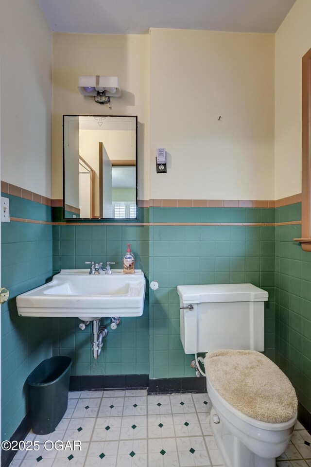 bathroom with tile patterned flooring, toilet, tile walls, and sink