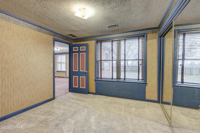 unfurnished room with carpet, a textured ceiling, and ornamental molding