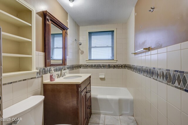 full bathroom with tile patterned flooring, a textured ceiling, toilet, vanity, and tile walls