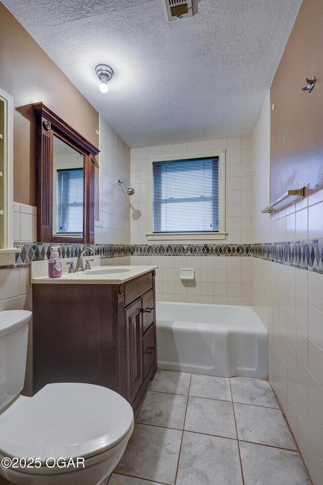 full bathroom featuring tile walls, tile patterned flooring, vanity, and a textured ceiling