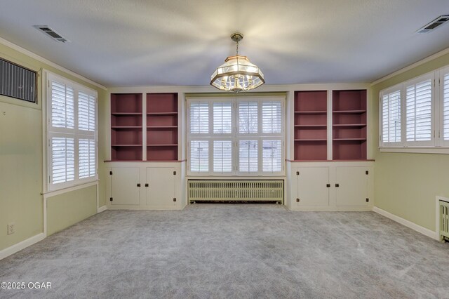 interior space with radiator, built in shelves, light colored carpet, a chandelier, and ornamental molding