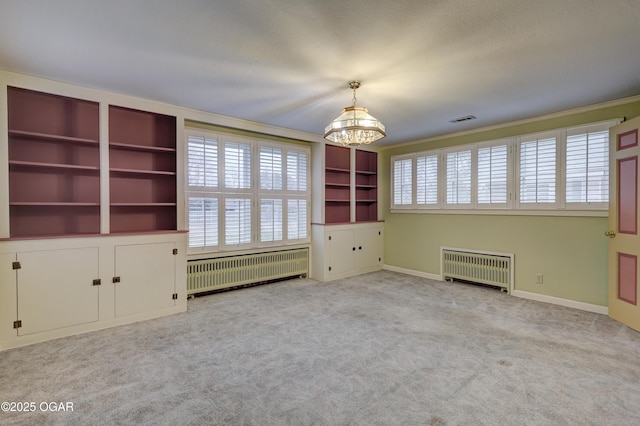 interior space featuring light carpet, radiator heating unit, and a notable chandelier