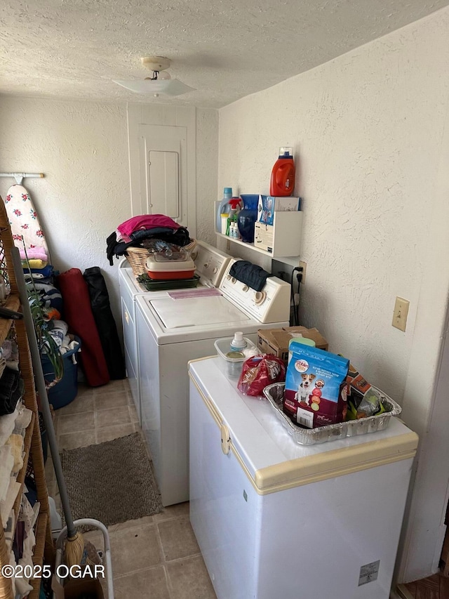 laundry room with washer and dryer, light tile patterned floors, and a textured ceiling